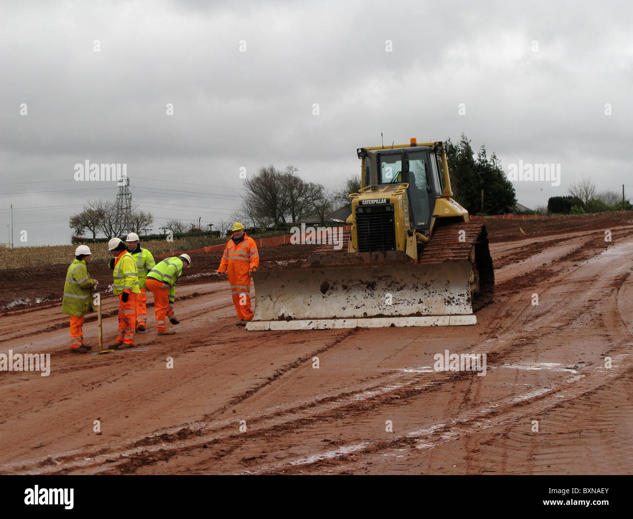 Ingegneria civile i lavoratori con un bulldozer sulla costruzione di strade site uk in inverno Foto Stock