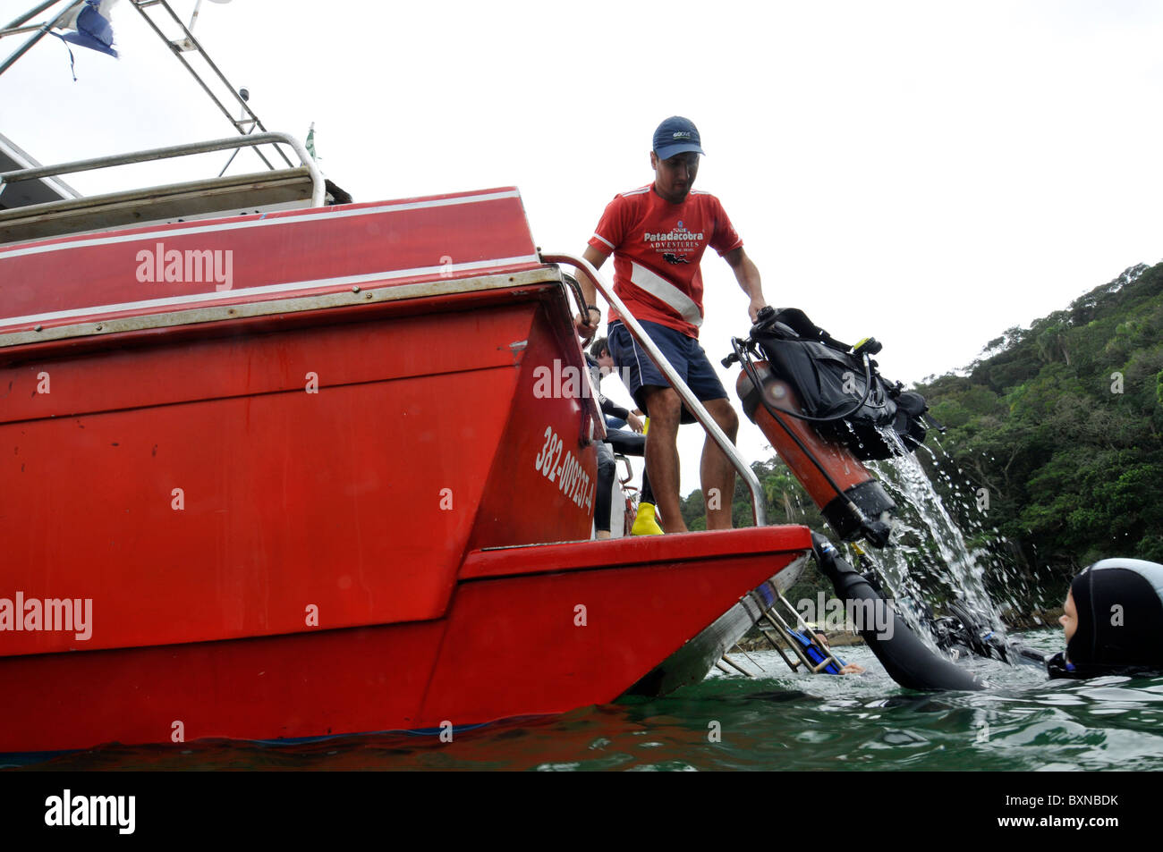 Il personale tira fuori del serbatoio di acqua come subacquei ritorno alla barca, Bombinhas, Santa Catarina, Brasile Foto Stock