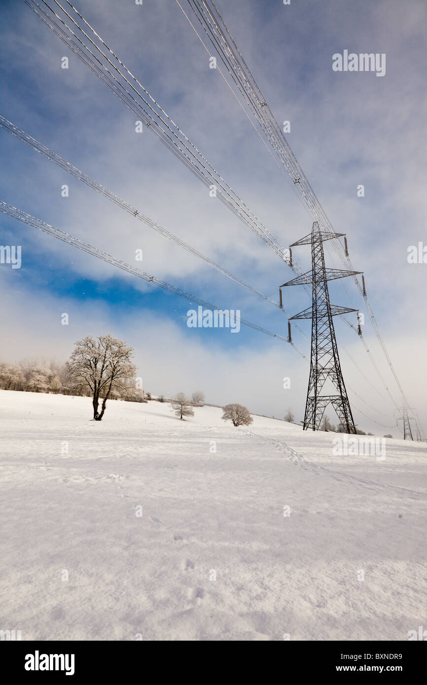 Elettricità tralicci seguenti nevicata fresca Foto Stock