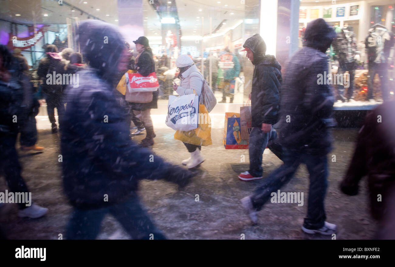 I Newyorkesi e visitatori di manovra attraverso la neve in Times Square a New York Foto Stock