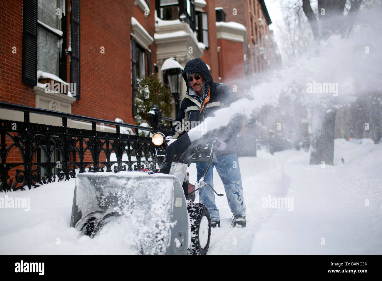 Un uomo utilizza uno spazzaneve a turbina per cancellare un marciapiede a seguito di una massiccia caduta di neve a Brooklyn, New York. Foto Stock