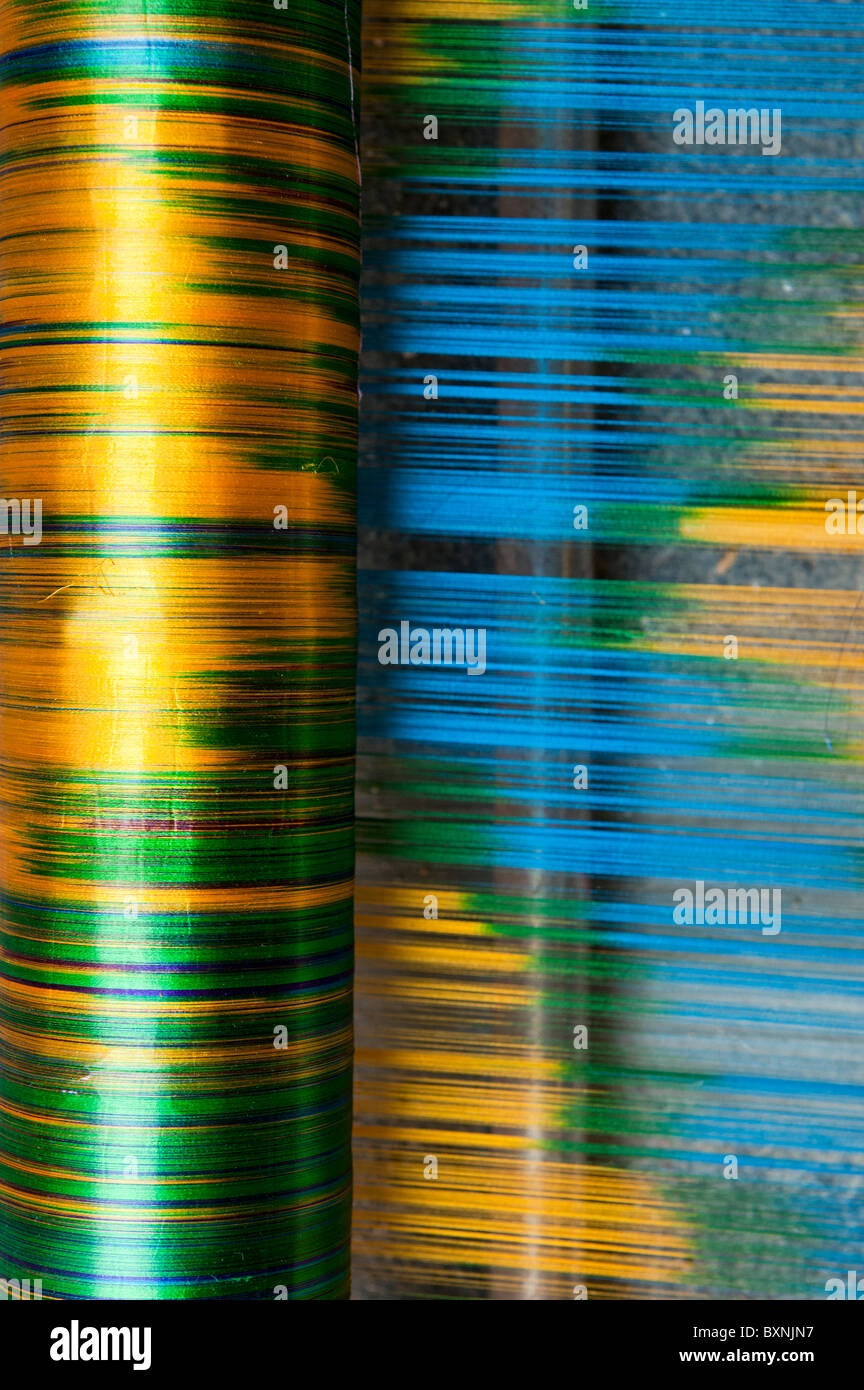 Filo di seta su di un telaio di tessitura a mano facendo un sari di seta in un Indiano cottage. Andhra Pradesh, India Foto Stock