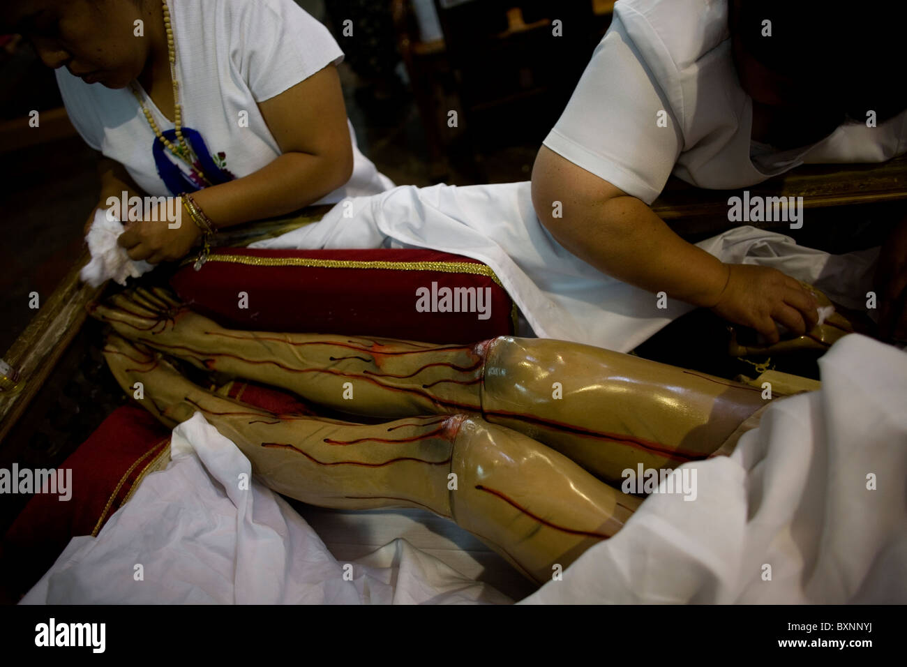 Le donne sfregano olio su una statua di Gesù Cristo dopo una settimana Santa processione in Oaxaca, Messico, 11 aprile 2009. Foto Stock