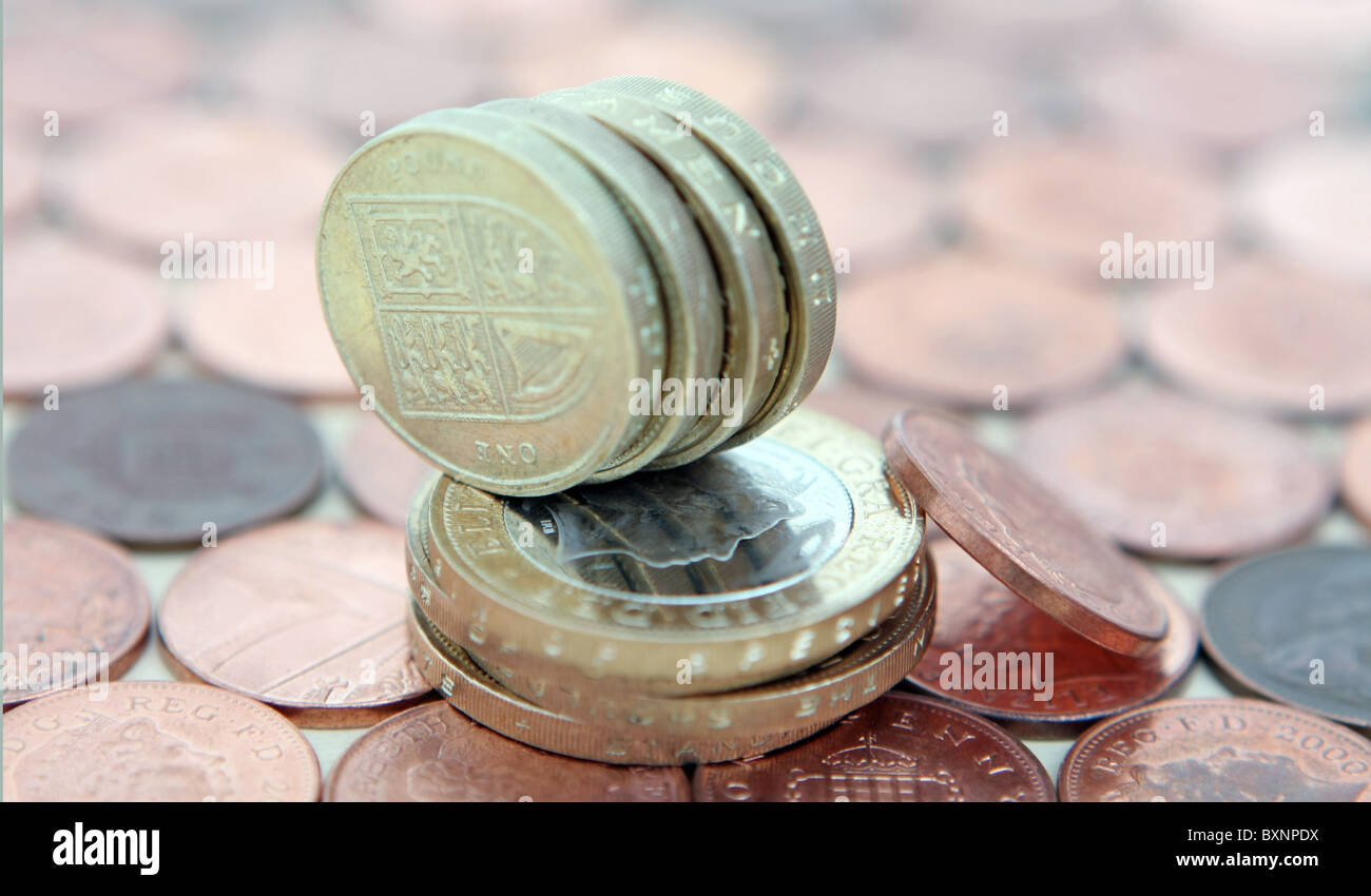 Una fila di sterling £1 monete su una pila di £ 2 monete e un 1p coin appoggiata contro il £2 monete - Tutto su uno sfondo di 1p delle monete in euro Foto Stock
