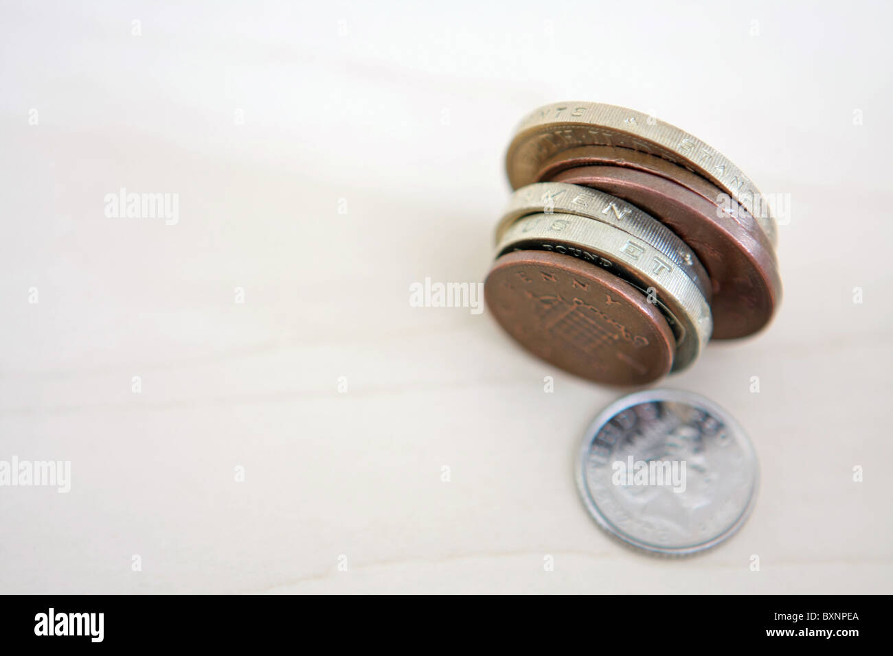Un allentamento sterling 5p coin accanto a qualche sterlina monete sulle estremità. Foto Stock