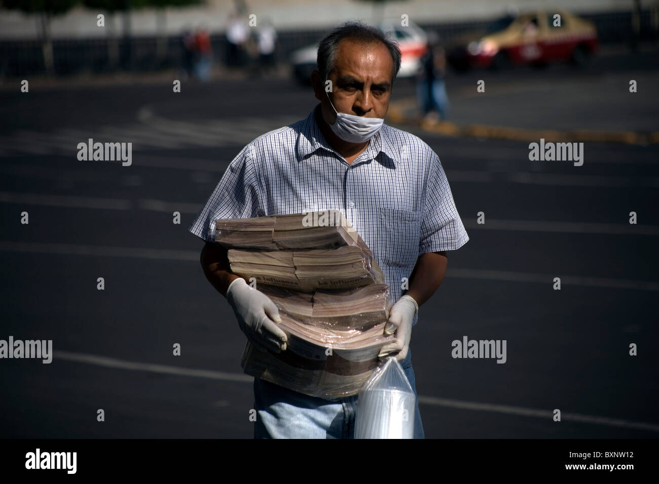 Un uomo che indossa una maschera come precauzione contro l influenza suina trasportare opuscoli informativi circa l'influenza in Città del Messico Foto Stock