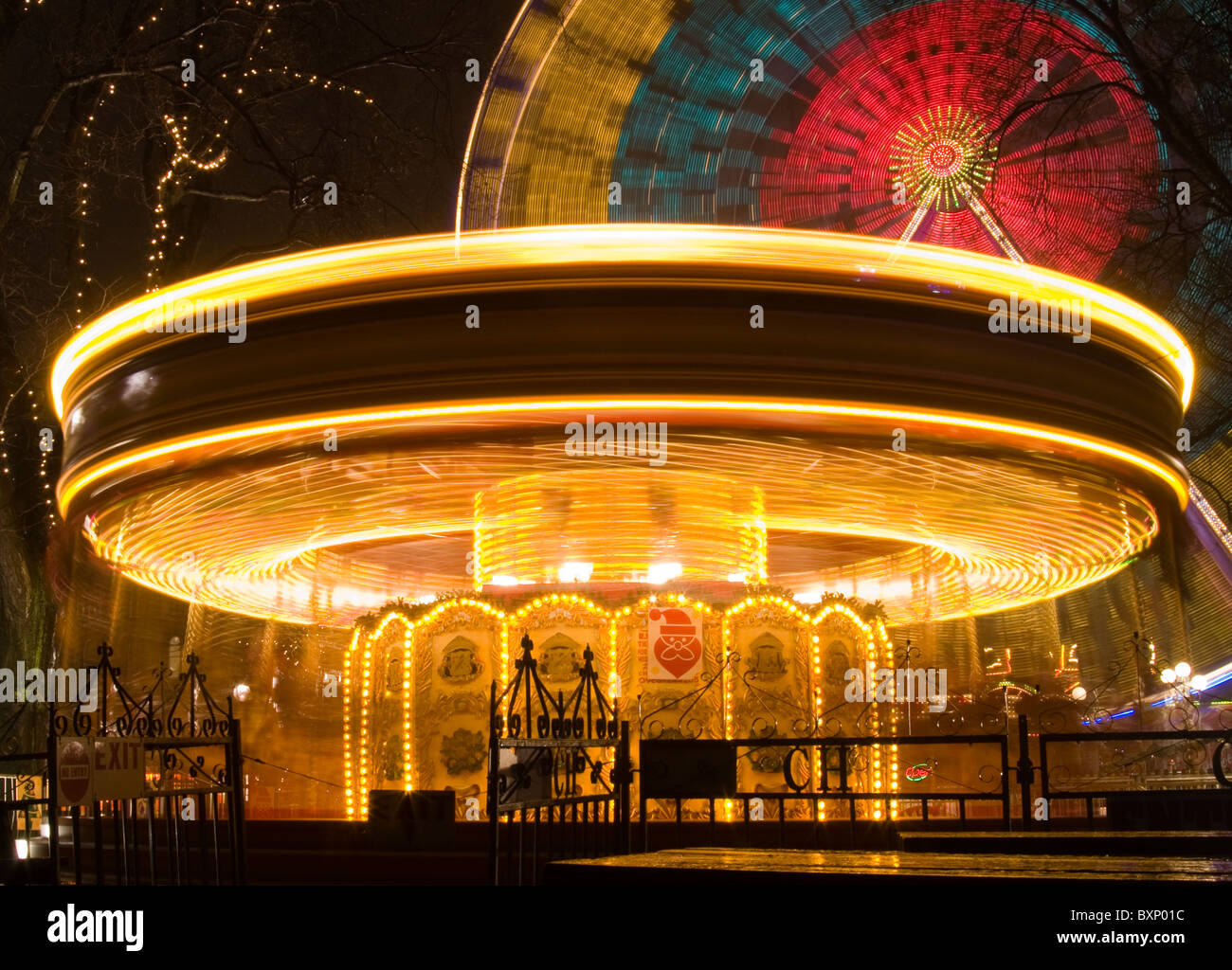 Merry Go Round illuminata di notte con ruota panoramica Ferris in background Foto Stock