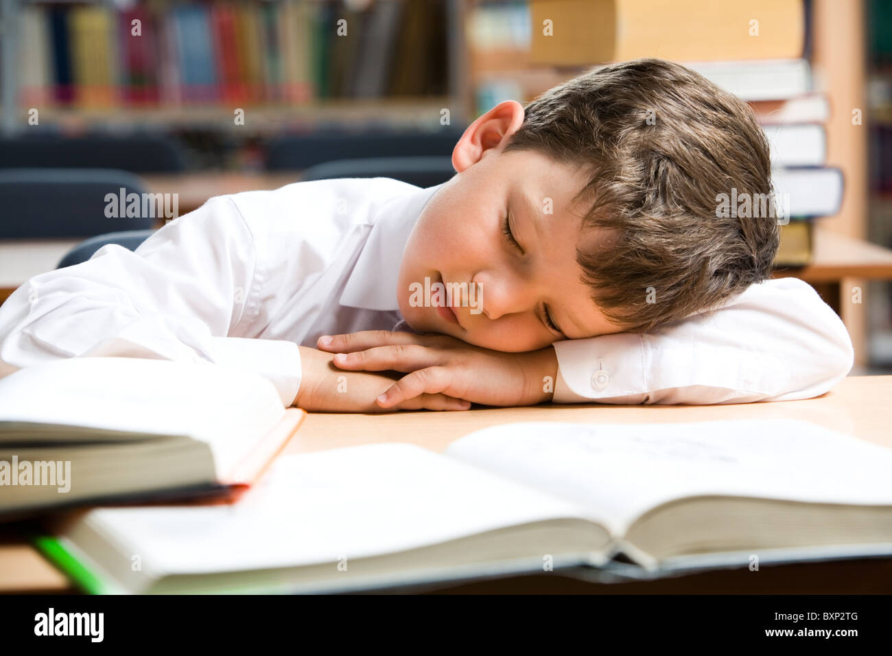 Immagine del giovane ragazzo dormire nei pressi di libri della biblioteca Foto Stock