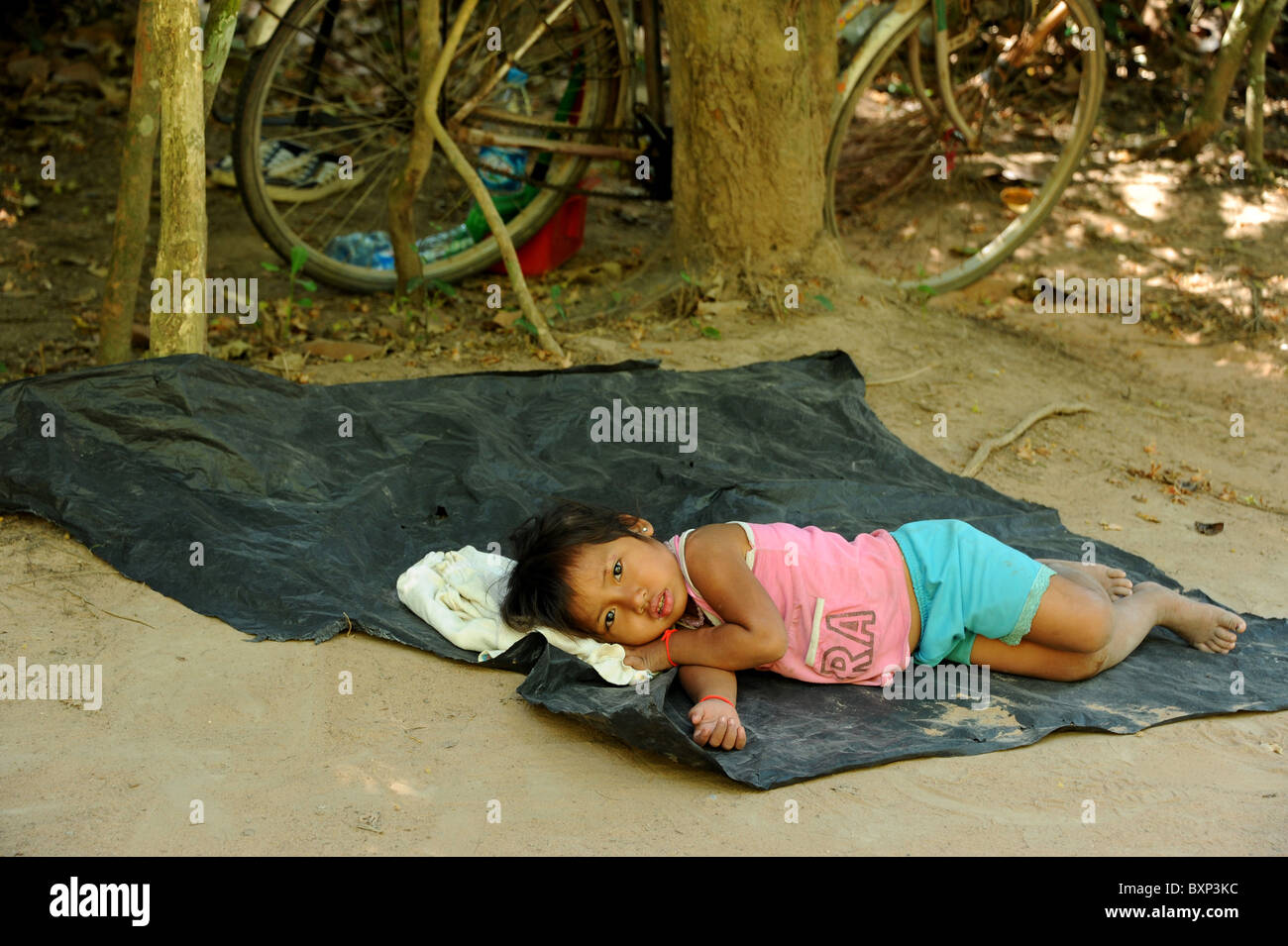 4 anno vecchia ragazza di riposo in ombra durante il mid-giorno calore nel Parco Archeologico di Angkor. Foto Stock