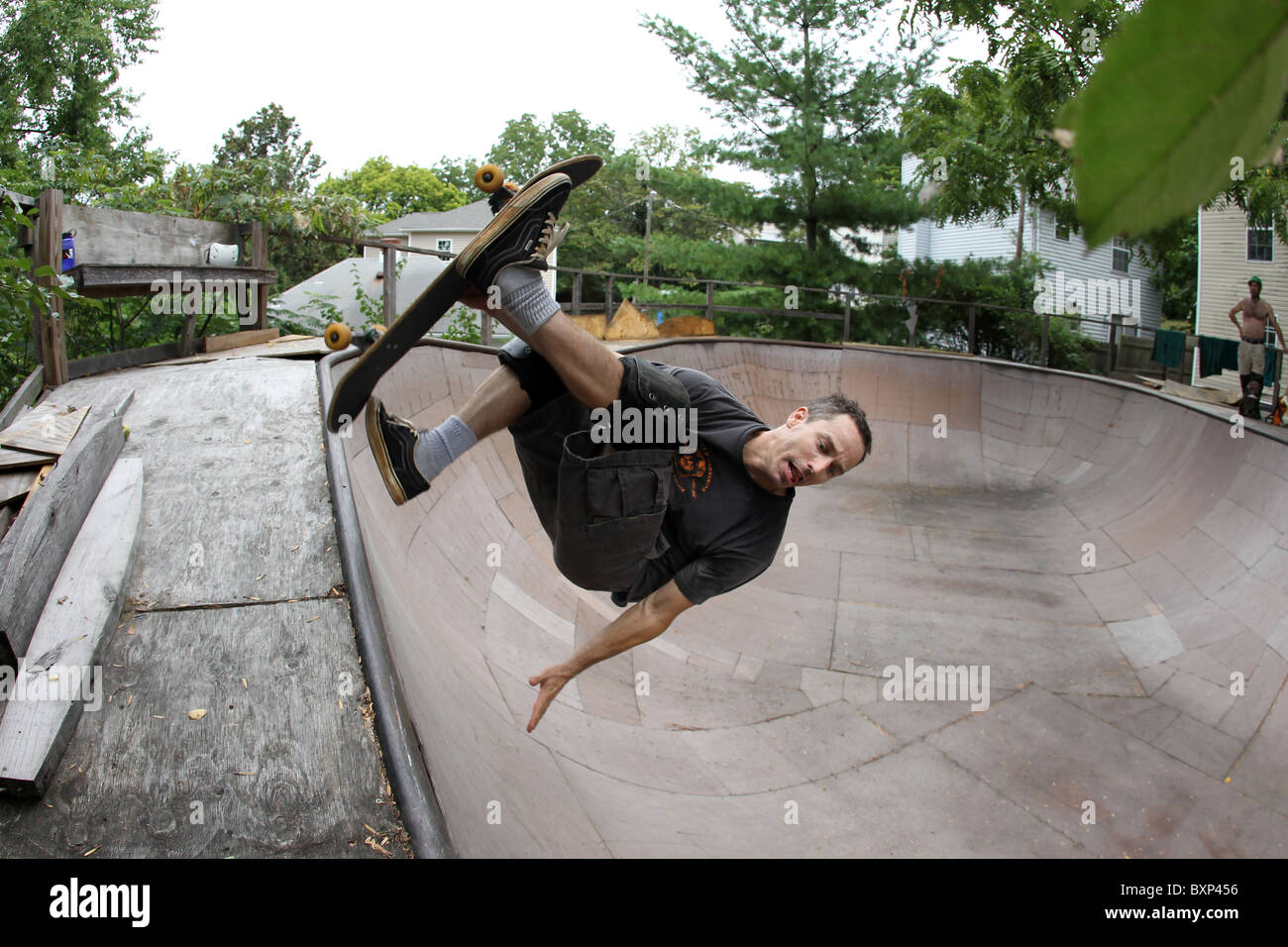 Guidatore di skateboard vola attraverso l'aria trucchi di preformatura su una rampa da skateboard in Charlottesville, VA. Foto Stock
