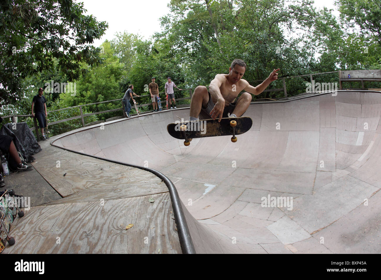 Guidatore di skateboard vola attraverso l'aria trucchi di preformatura su una rampa da skateboard in Charlottesville, VA. Foto Stock