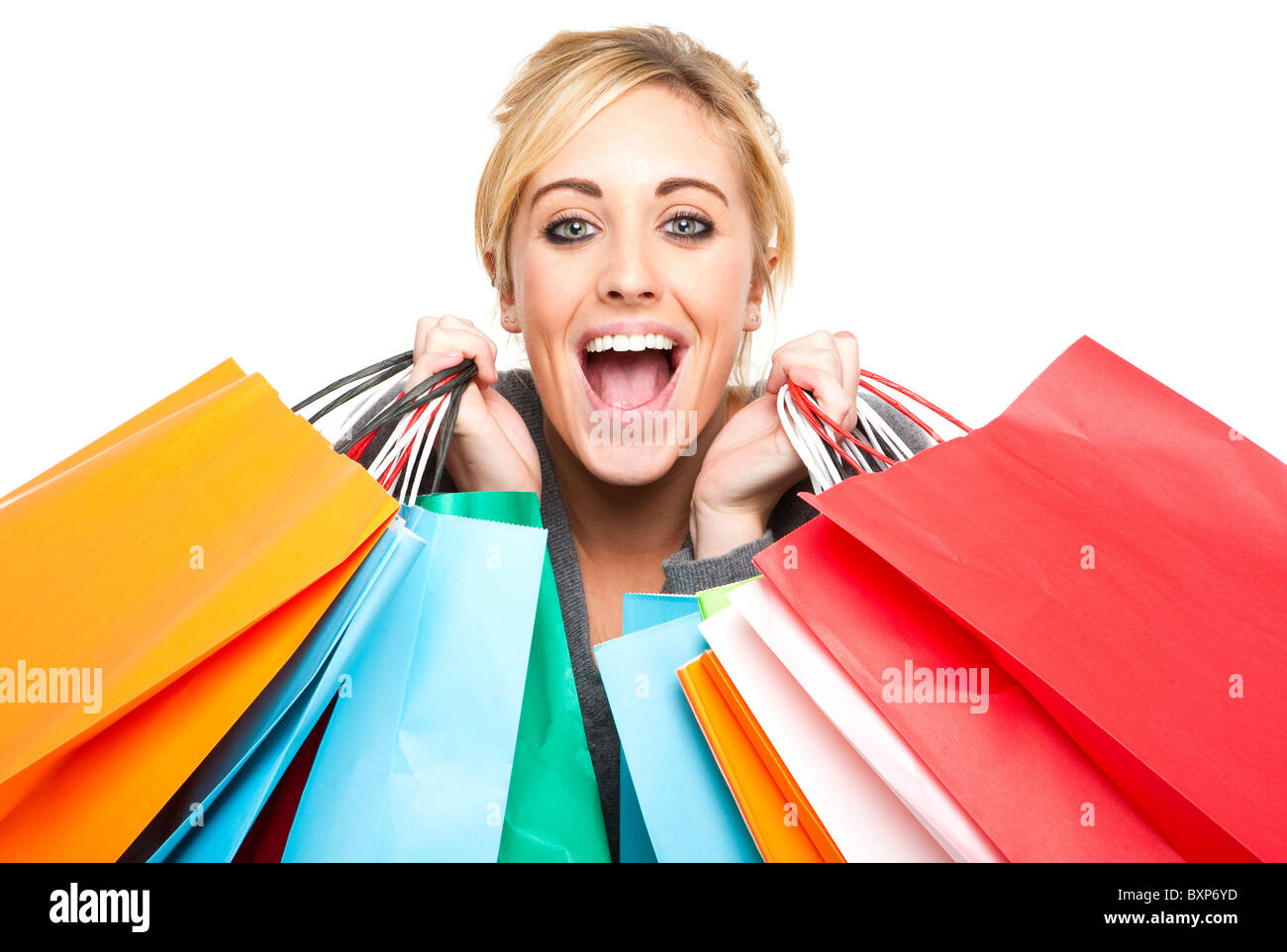 Attraente giovane donna bionda di caricarti di Multi-Colored Shopping Bags cercando felice ed entusiasta Foto Stock