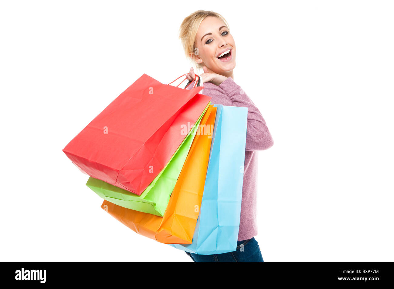 Attraente giovane donna bionda di caricarti di Multi-Colored Shopping Bags cercando felice ed entusiasta Foto Stock