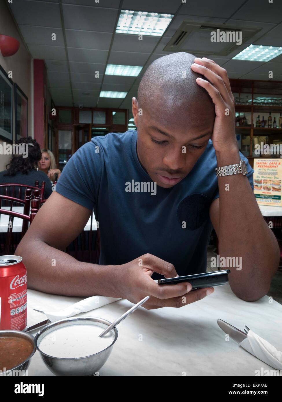 Uomo che utilizza Internet nella sua smart telefono cellulare in un ristorante fast food Foto Stock