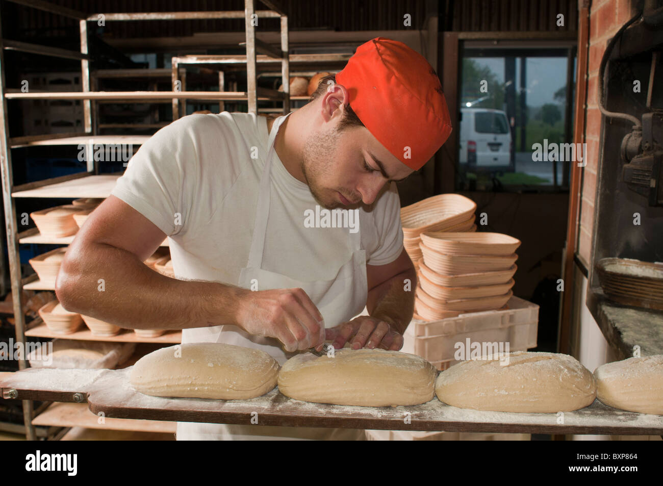 Artigiano panettiere di pasta acida abbattono le cime di pani in procinto di essere caricato in una stufa a legno Foto Stock