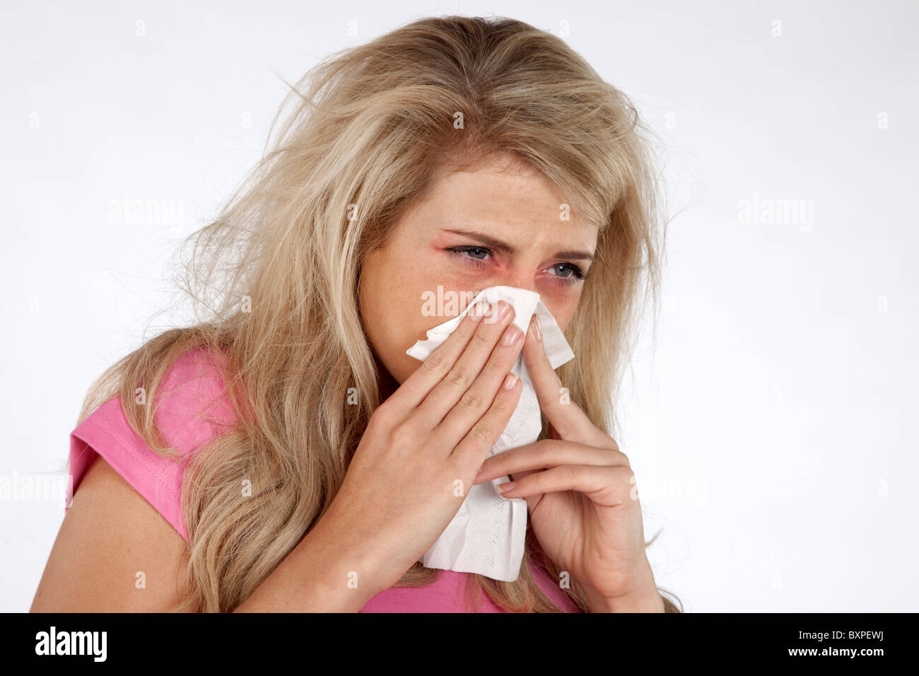 Giovane donna bionda con un freddo starnuti e soffiare il naso su un tessuto Foto Stock