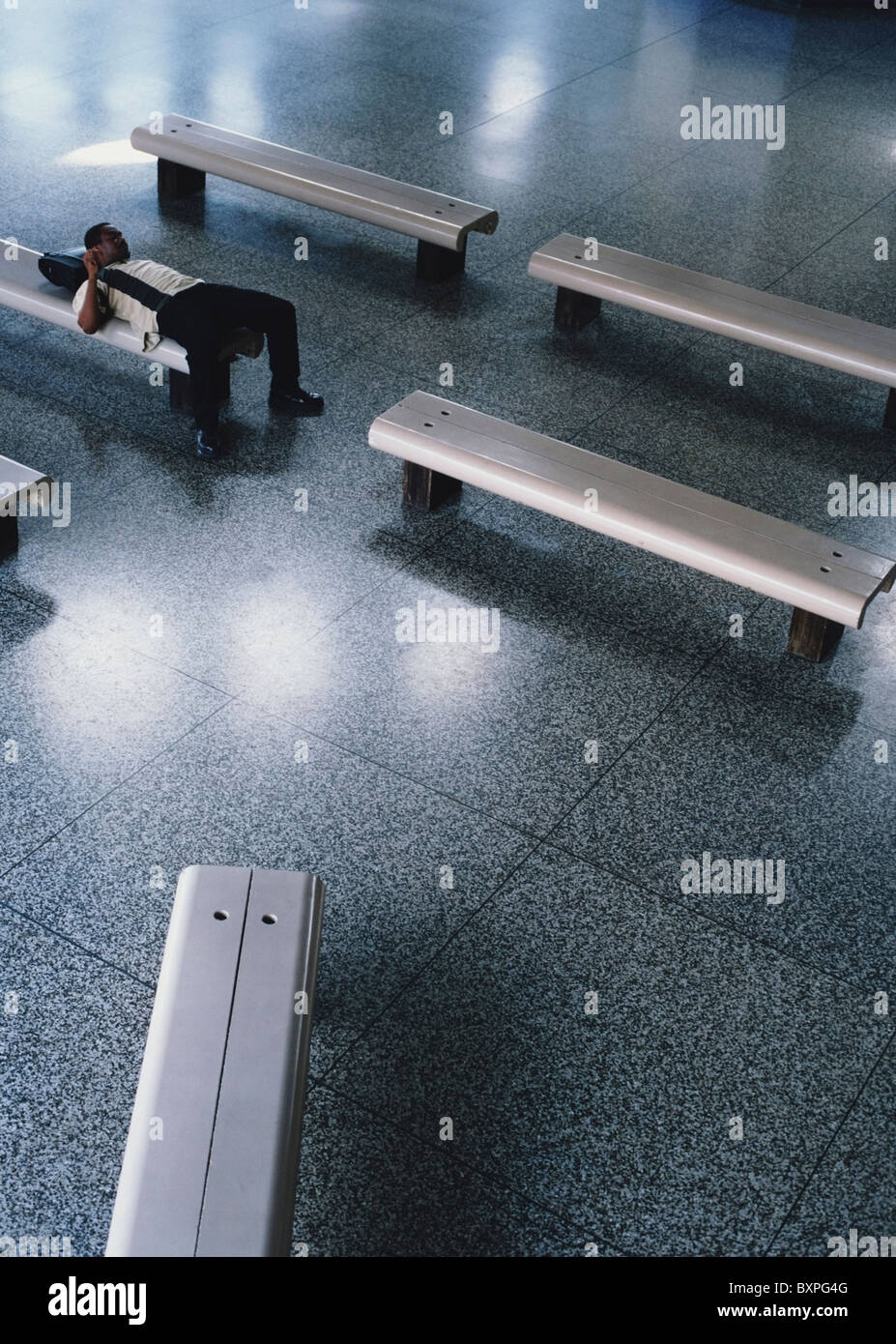 Uomo disteso sul banco in aeroporto Foto Stock