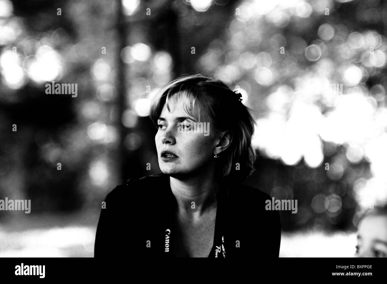 Romantico ritratto di donna bella nel parco con una fascetta di Canon sul collo. Sonnar Bokeh sfondo. Foto Stock