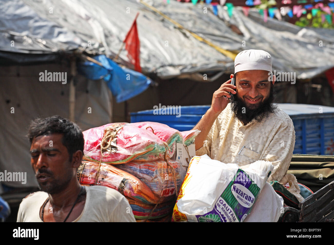 Uomo commerciante musulmano sul telefono mobile sul retro di risciò umano in strada, Calcutta, India Foto Stock