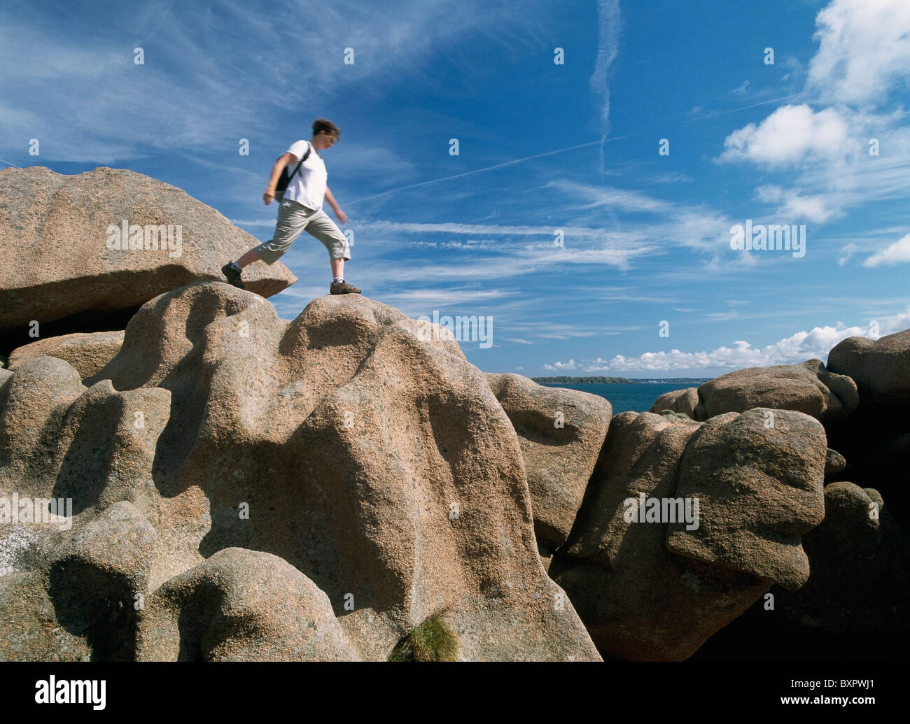Donna Walker saltando su formazioni rocciose, basso angolo di visione Foto Stock