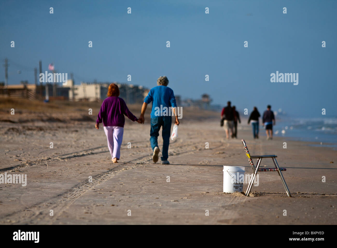 Un paio di camminare mano nella mano facendo una passeggiata invernale lungo una spiaggia della Florida Foto Stock
