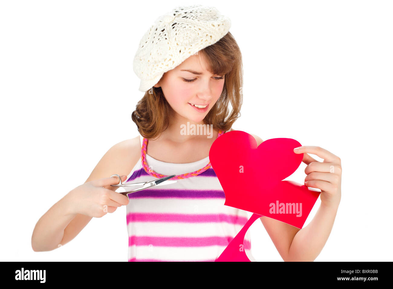 Ragazza carina nel cappuccio di taglio cuore di San Valentino al di fuori della carta rossa con le forbici Foto Stock