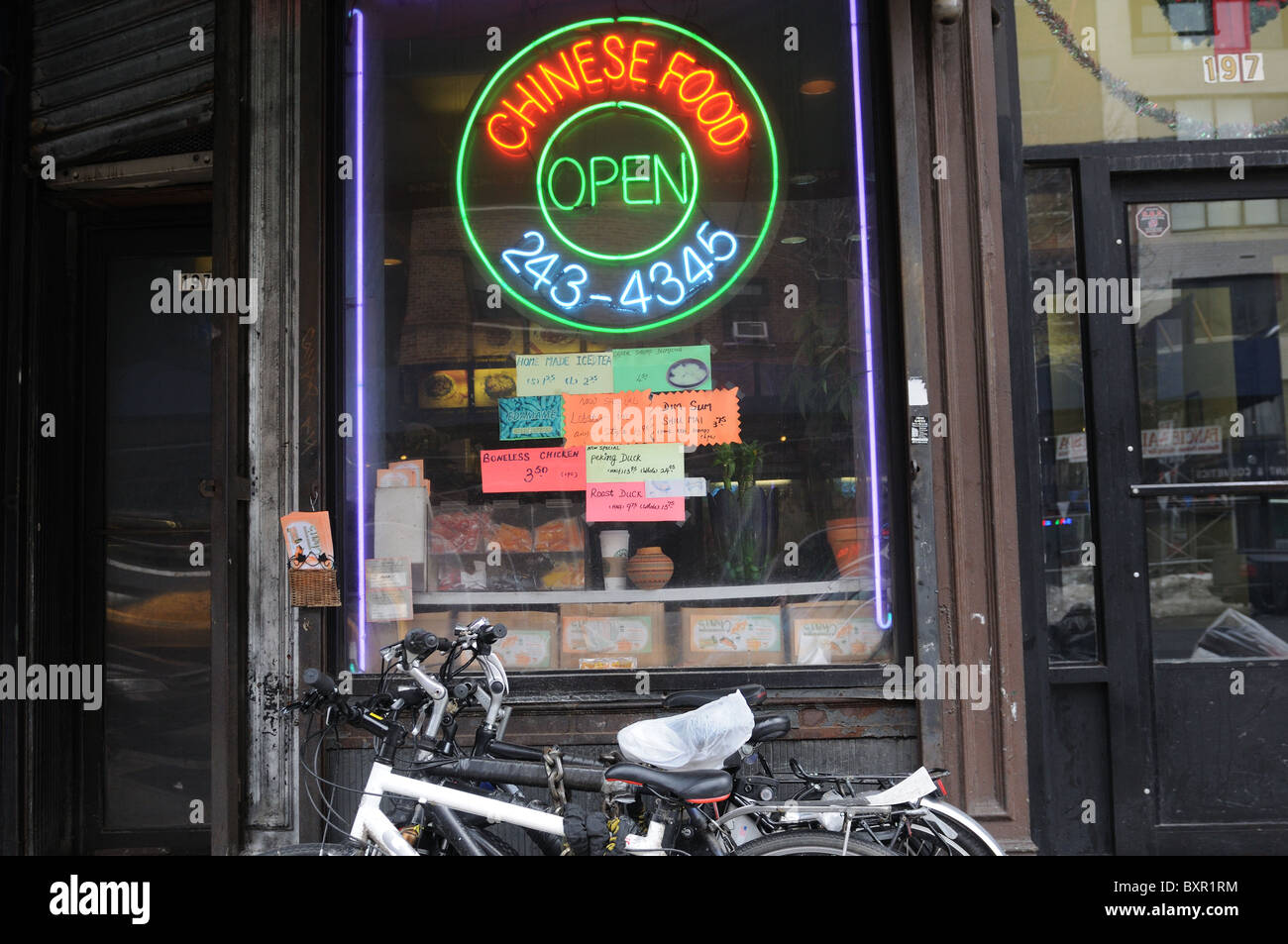 Un ristorante Cinese sulla Settima Avenue a Manhattan con le biciclette utilizzate da consegna Uomini incatenati al di fuori. Foto Stock