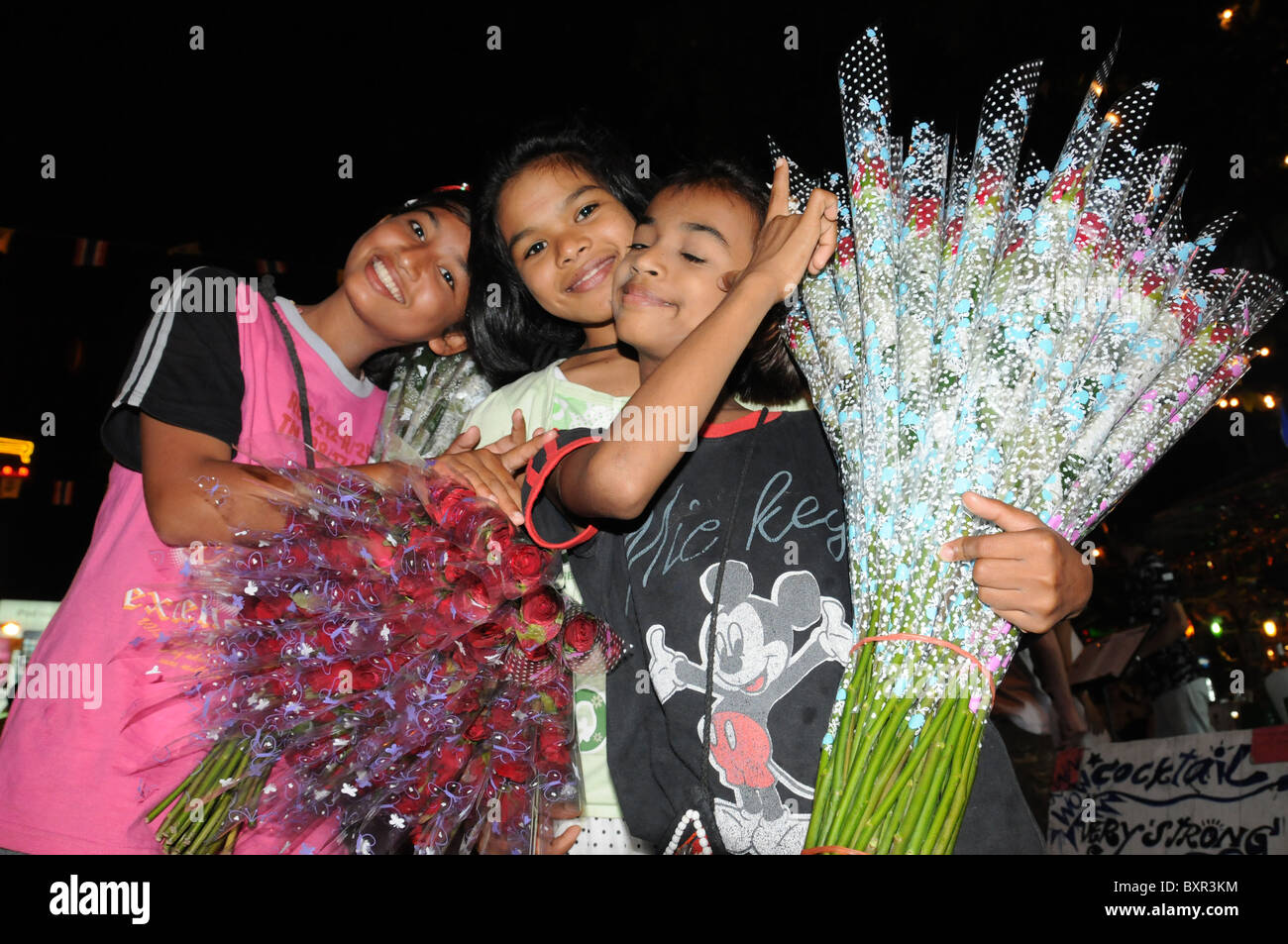 Giovani bambini che vendono le rose in Khaosan Road di Bangkok di notte Foto Stock