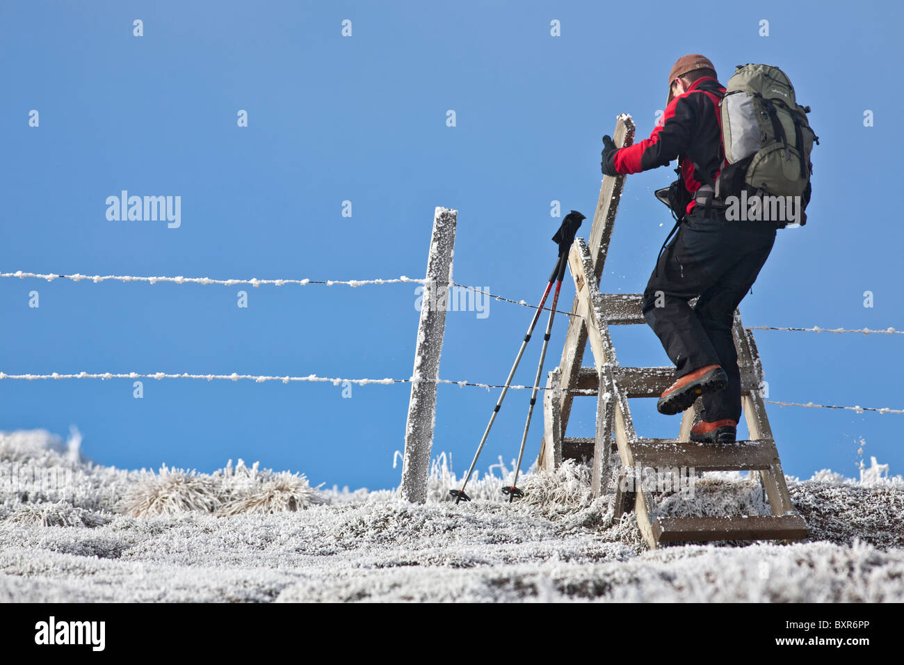 Nella valle di Chaudefour, un escursionista superando un cancello in inverno (Auvergne-France). Stile di legno. Foto Stock