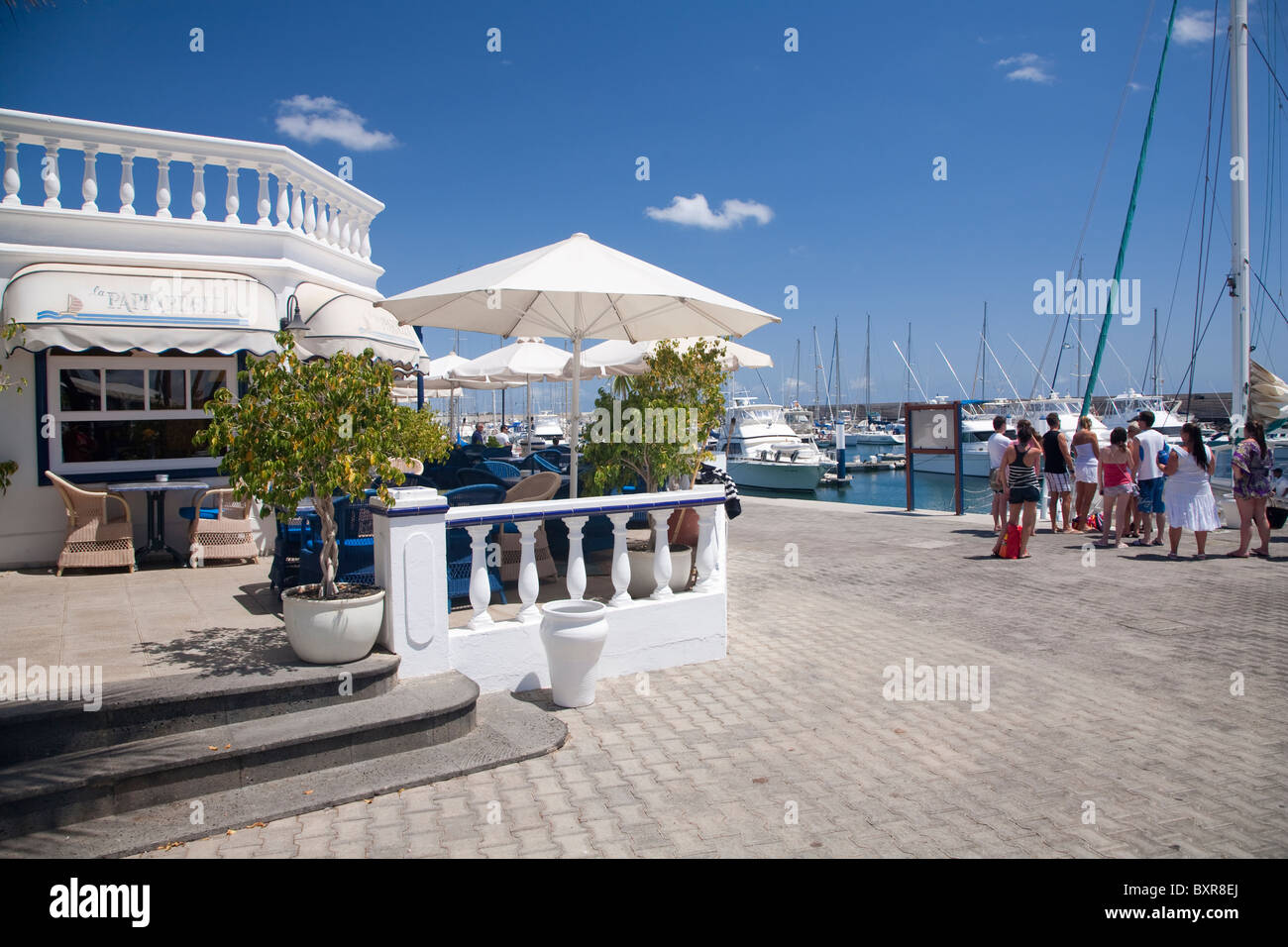Ristorante e waterfront , con i turisti in coda per un viaggio di yacht a Puerto Calero Marina, Lanzarote Foto Stock