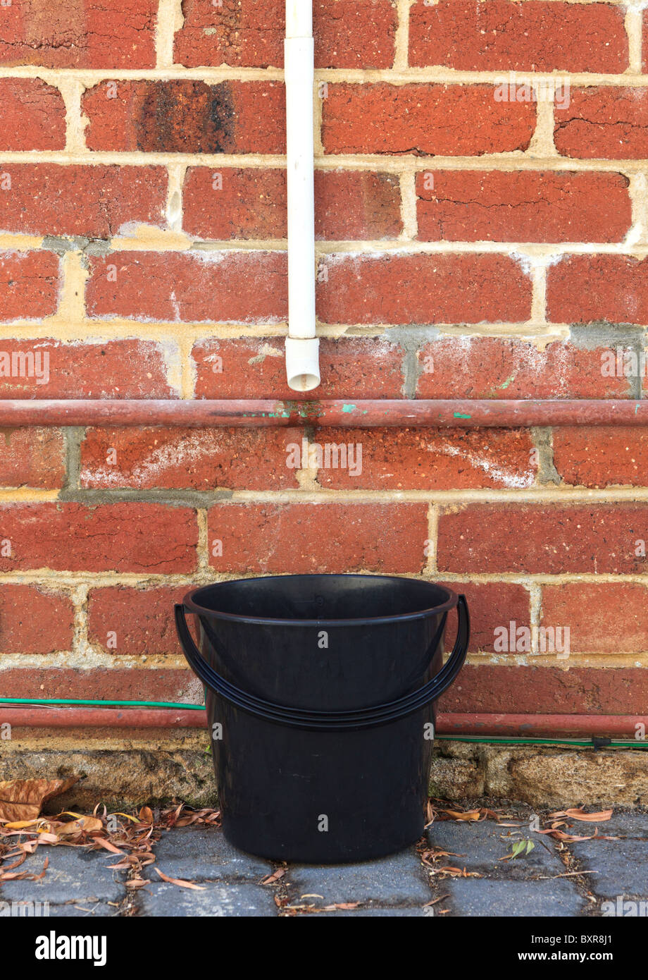 Un cucchiaio di acqua di raccolta per il riutilizzo al di sotto di un condizionatore di aria della tubazione di uscita. Foto Stock