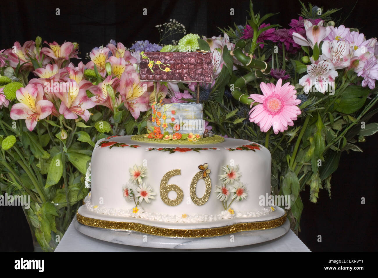 Un sessantesimo compleanno torta con Wishing Well sulla parte superiore e i fiori recisi in background Foto Stock
