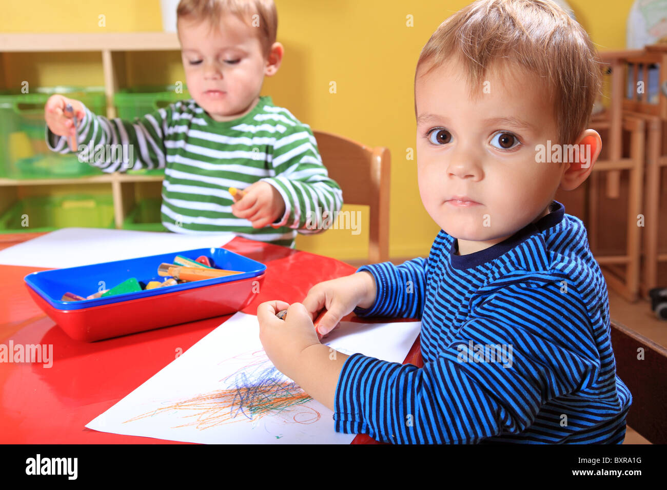 Carino unione toddlers il disegno di una foto in una scuola materna. Foto Stock