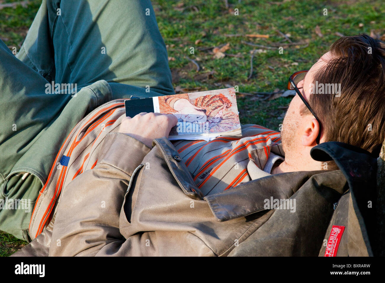 Studente di College dormendo mentre la lettura di un classico di Central Park, Manhattan Foto Stock
