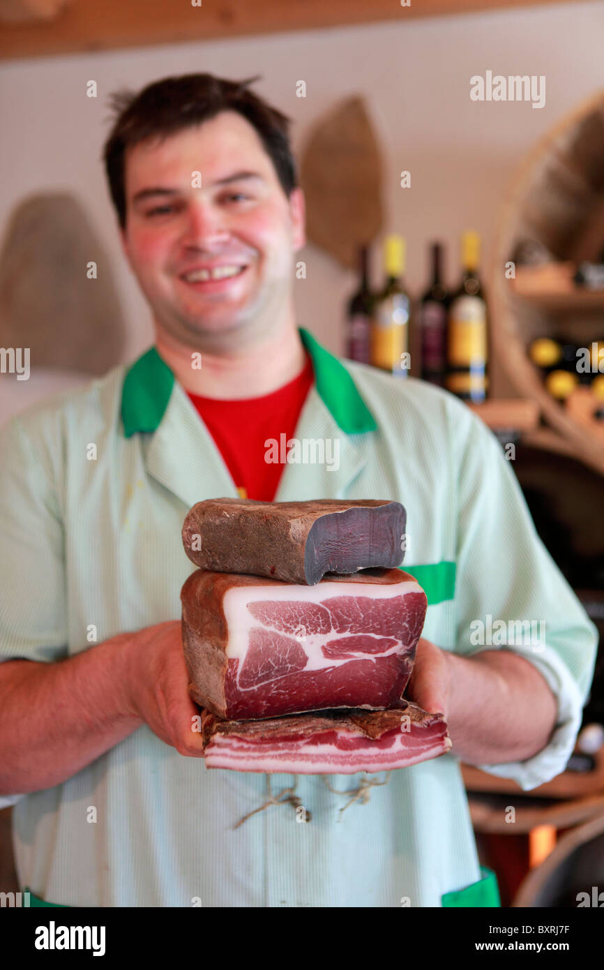 Un macellaio contiene una selezione di carne secca e pancetta affumicata alla macelleria di Val d'Anniviers in Vissoie, Svizzera Foto Stock