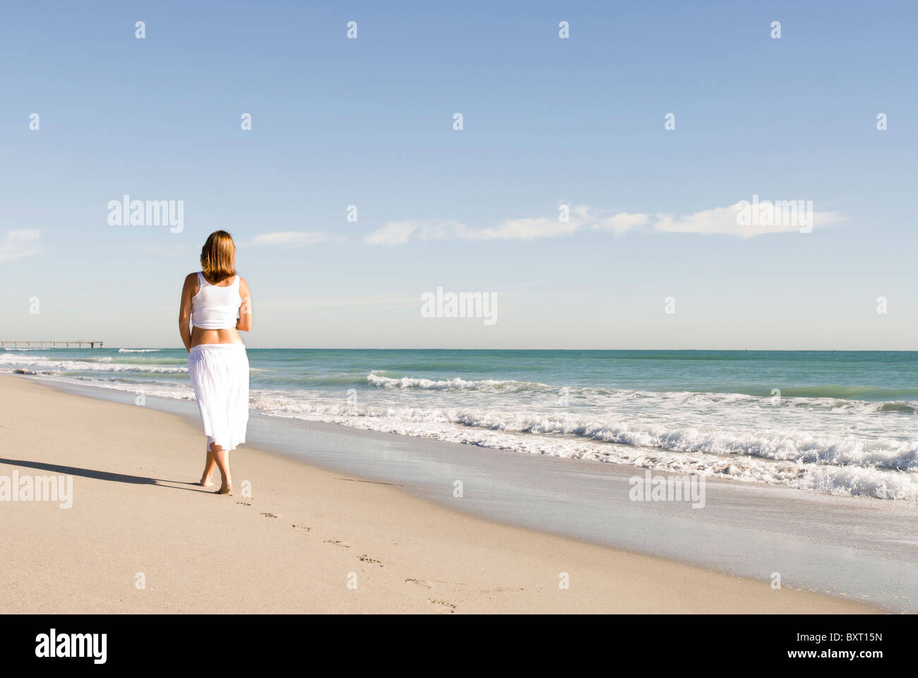 Donna incinta camminando sulla spiaggia Foto Stock