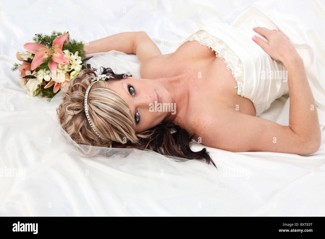 Giovane sposa caucasica posa su abito bouquet di contenimento di close-up Foto Stock