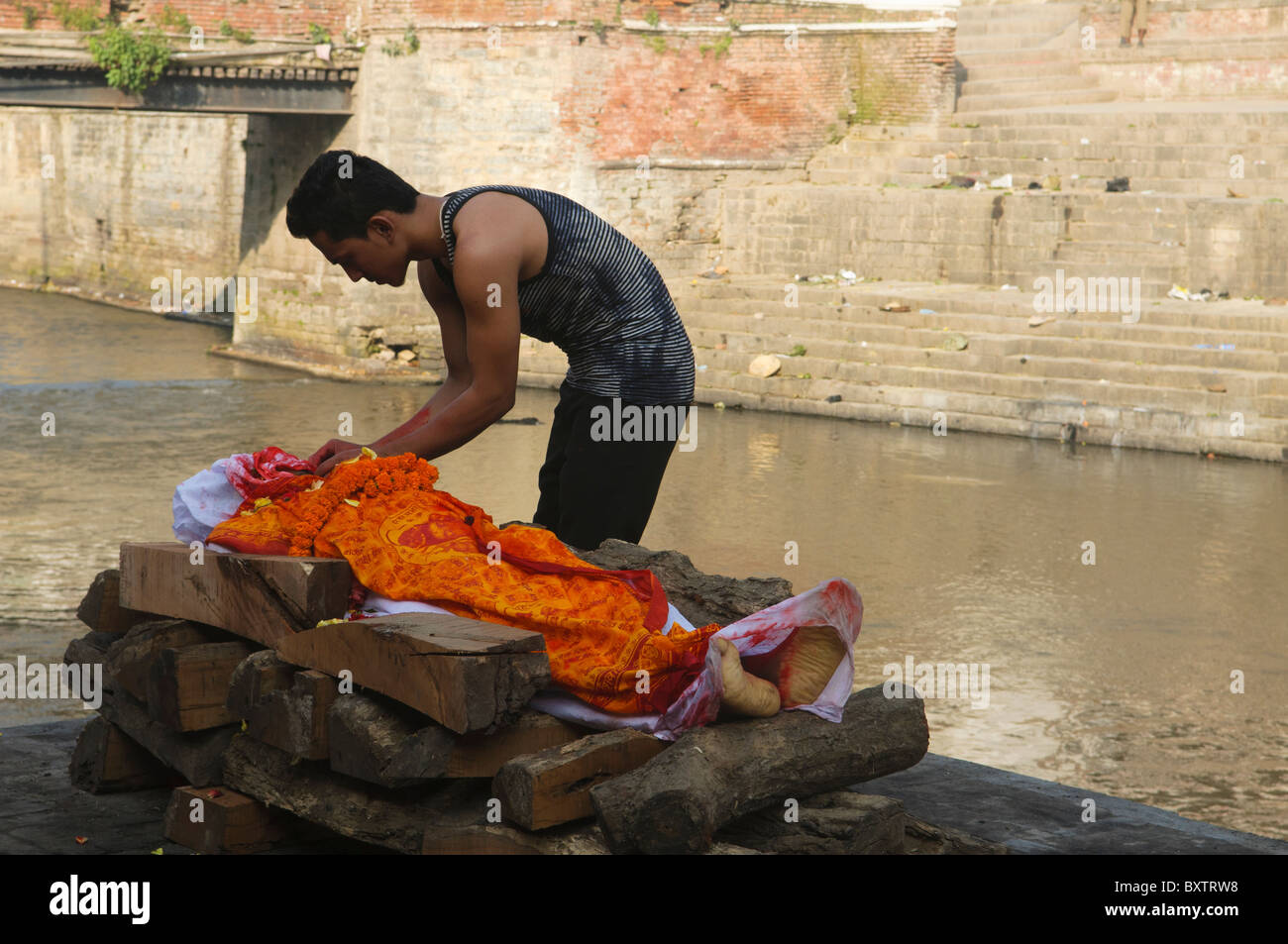 Un figlio dice addio a un funerale cremazione sul fiume Bagmati presso il Tempio Pahsupatinath a Kathmandu in Nepal Foto Stock