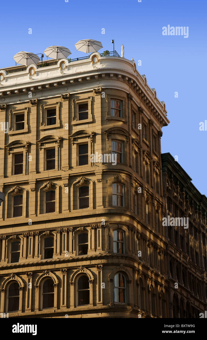 Verticale di diverse storie di un vecchio hotel elegante che mostra superbe architetture di dettagli con la terrazza sul tetto contro il cielo blu. Foto Stock