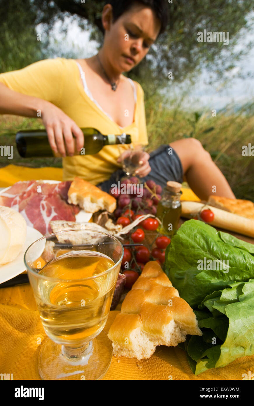 Donna versando una bottiglia di vino in preparazione per il Picnic sotto gli ulivi Foto Stock