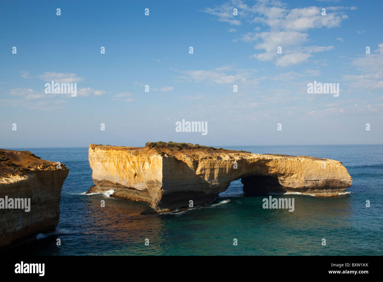 Australia Victoria Parco nazionale di Port Campbell onde dal Mare di Tasman alla base del London Bridge formazione di roccia su mattinata estiva Foto Stock