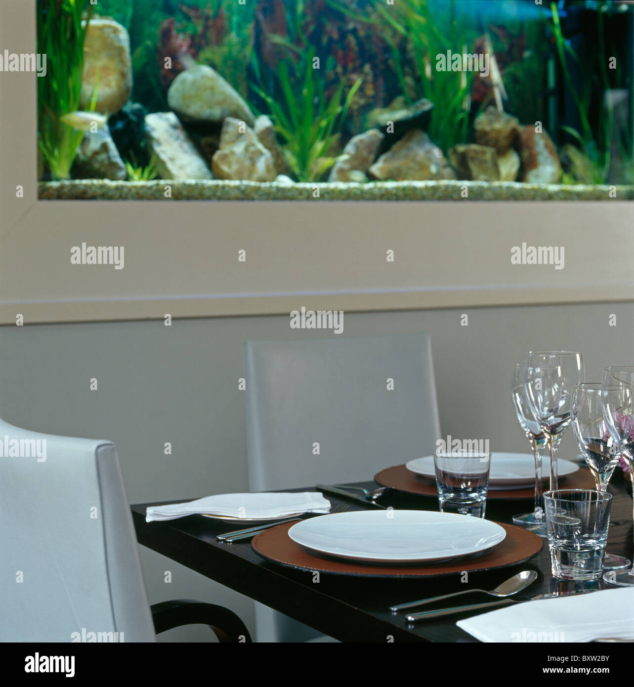 Close-up di piastre bianche e vino-bicchieri sulla tavola nera impostata per il pranzo in una moderna sala da pranzo Foto Stock