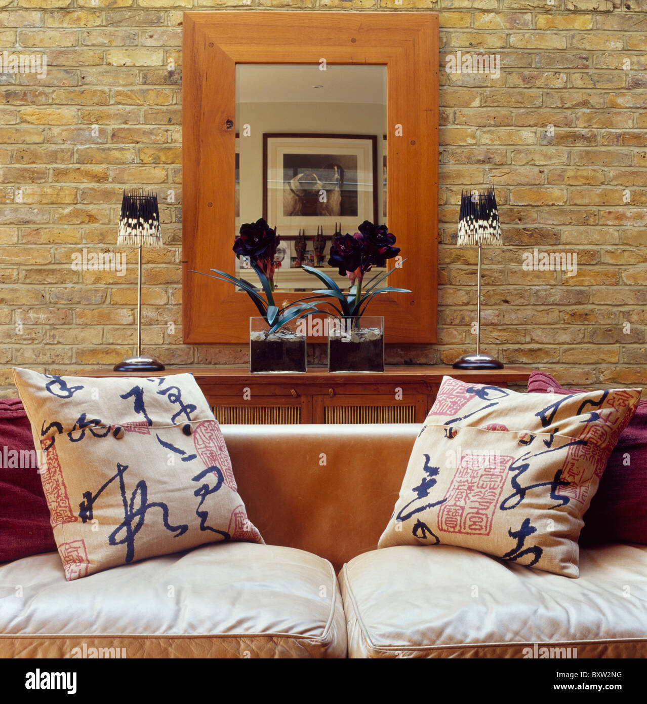 Divano con blue+cinese bianca-scritte cuscini modellato in soggiorno con  grande legno-specchio incorniciato esposta su un muro di mattoni Foto stock  - Alamy