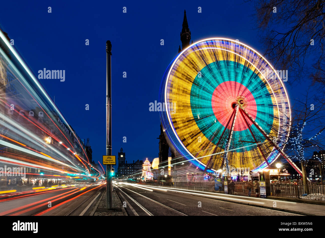 La ruota di Edimburgo di fronte al monumento di Scott con traffico sfocate su Princes Street, Edimburgo, Scozia, Regno Unito. Foto Stock
