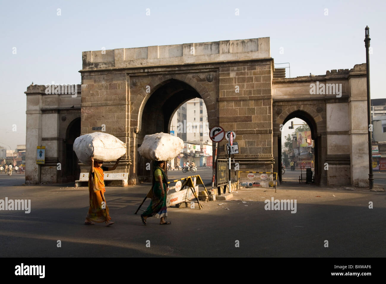 Le donne indiane in sarees borse per il trasporto sulle loro teste in modo tradizionale a Delhi Darwaja in Ahmedabad, Gujarat, India. Foto Stock