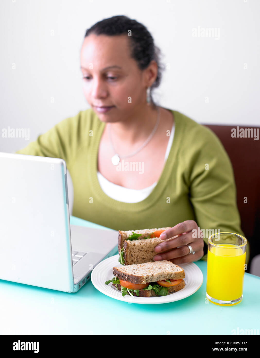 Donna al computer con un sandwich di insalata Foto Stock