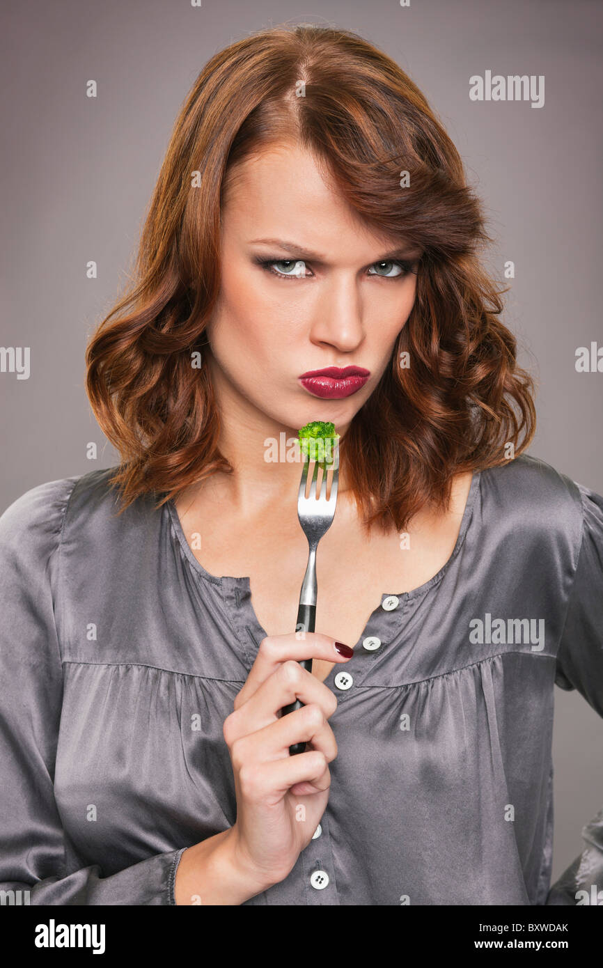 Giovane donna di mangiare i broccoli Foto Stock