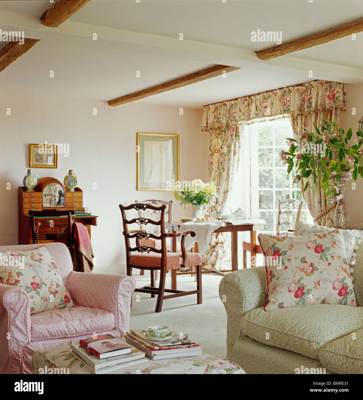 Rosa cuscini floreali sulla poltrona rosa e verde pallido divano in cottage soggiorno con tappeto color crema Foto Stock