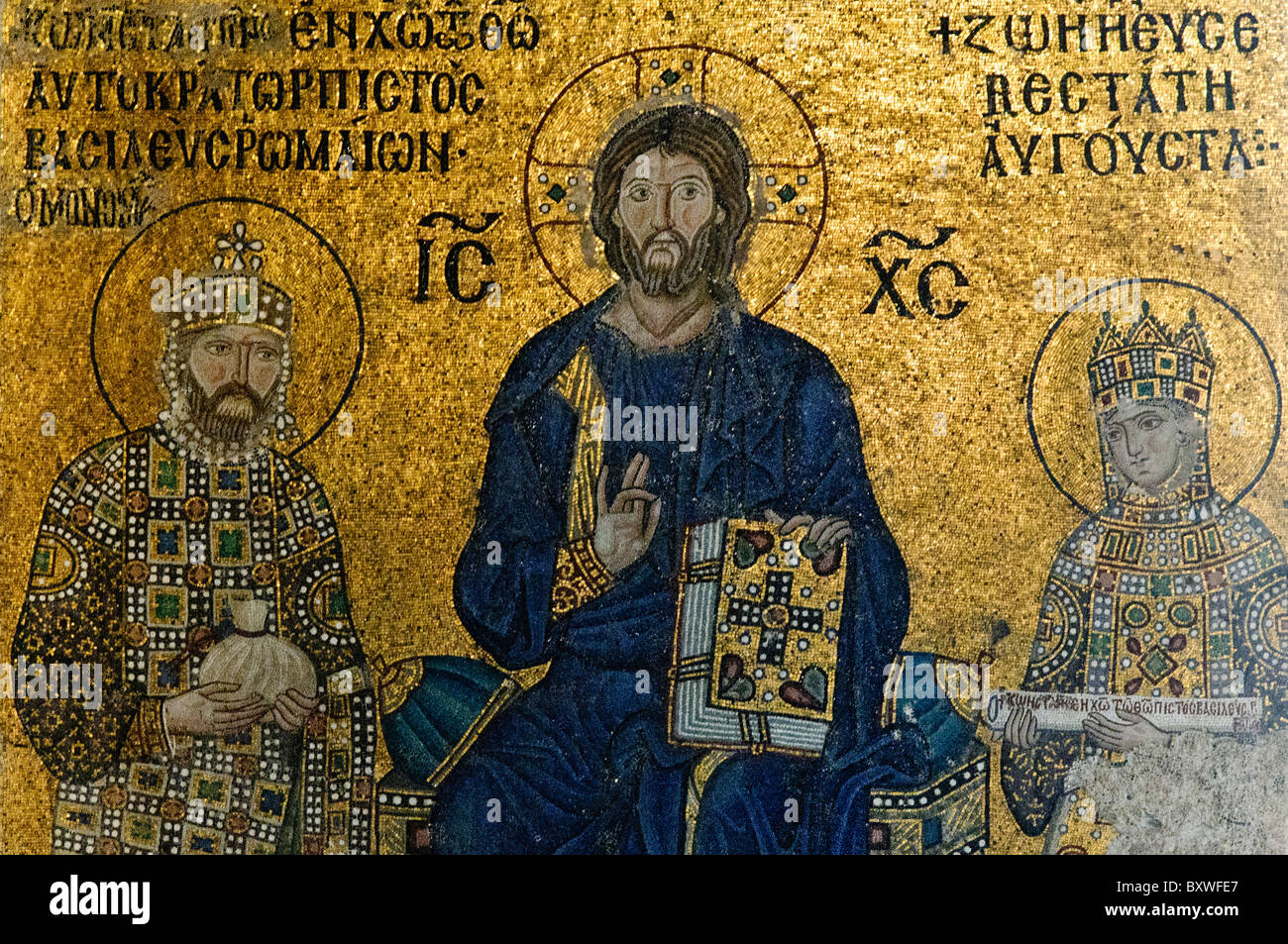 Hagia Sophia Mosaico bizantino Cristo Istanbul Turchia // ISTANBUL, Turchia — Un mosaico bizantino nella Basilica di Santa Sofia raffigura Cristo che tiene un libro e fa un gesto di benedizione, affiancato da due figure imperiali. Il mosaico dimostra l'uso sofisticato delle tessere d'oro caratteristiche delle tecniche artistiche bizantine. La ritrattistica dettagliata e le iscrizioni greche riflettono la storia dell'edificio come chiesa principale dell'Impero bizantino. Foto Stock