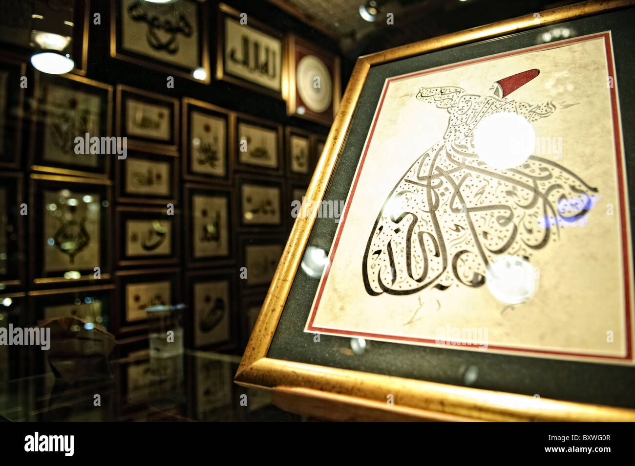 Rolling Dervish Calligraphy Art Grand Bazaar Istanbul // ISTANBUL, Turchia — un negozio d'arte nello storico Grand Bazaar di Istanbul vende illustrazioni, dipinti e calligrafia. Quello in primo piano è dei famosi ballerini Whirling Dervish della città. Il Grand Bazaar, uno dei mercati coperti più grandi e antichi del mondo, è un vivace centro commerciale e culturale di Istanbul. Caratterizzato da un labirinto di oltre 4.000 negozi, offre una vivace gamma di prodotti, da spezie e gioielli a tessuti e ceramiche. L'architettura storica e l'atmosfera vivace del Grand Bazaar attirano milioni di visitatori Foto Stock